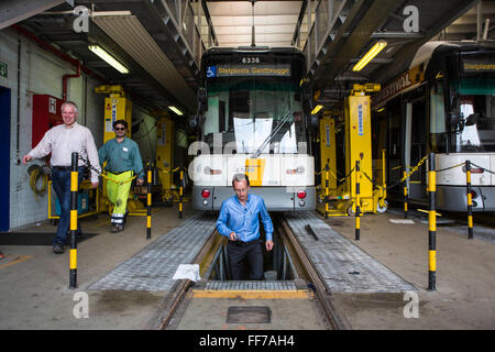 Patrick De Boeuf, Chief Executive von De Lijn, Schritte bis aus dem Boxenbereich Workshop unter einer modernen Straßenbahn zwei Männchen entlang die Straßenbahn in das Depot in Gentbrugge, Gent, Belgien.  Die Straßenbahnen wurden modernisiert, um den Stromverbrauch zu reduzieren und gewann eine Auszeichnung für nachhaltiges Reisen von Ashden. Stockfoto