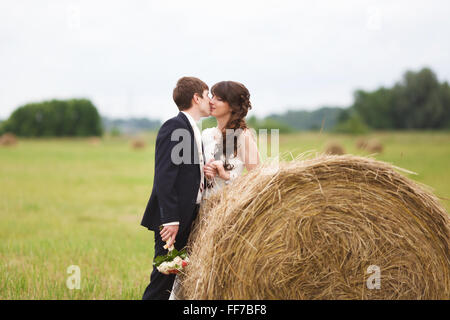 Braut und Bräutigam in der Nähe von Heu auf einem ländlichen Gebiet Stockfoto