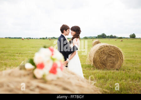 Braut und Bräutigam in der Nähe von Heu auf einem ländlichen Gebiet Stockfoto