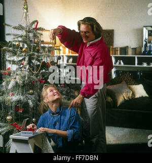 Weihnachten, Weihnachtsbaum / Weihnachtsbaumschmuck, junges Paar, das Weihnachtsbaum schmückt, 1980er Jahre, Zusatzrechte-Clearences-nicht vorhanden Stockfoto