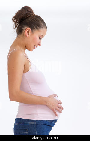 Schwangere Asiatin suchen und ihren Bauch zu berühren Stockfoto