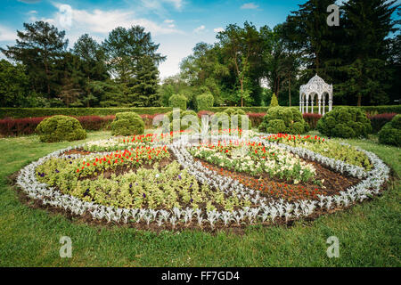 Pavillon im grünen Frühling Sommergarten. Garten Pergola mit Wald im Hintergrund und Blume Bett im Vordergrund Stockfoto