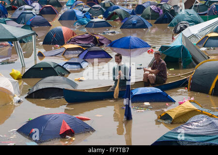 Plünderer in einem kanadischen Kanu Suchfeld von überfluteten Zelten auf dem sehr nassen 2005 Glastonbury Festival. Stockfoto