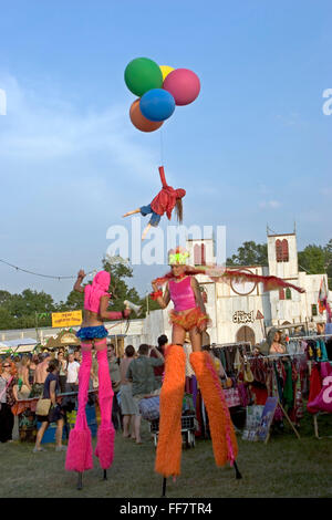 Zwei Stelzenläufer Künstler und der Künstler Bansky, mit seinem Markenzeichen-Mädchen mit Luftballons, gehen vorbei an der Kapelle der Liebe & Schrecken in verloren Unbestimmtheit auf dem Glastonbury Festival. Stockfoto