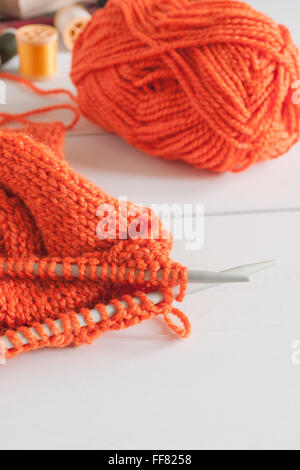 Stricken Strickjacke mit Nadeln und Kugeln von Orange wolle eine Stricknadel oder Handarbeit Konzept Stockfoto