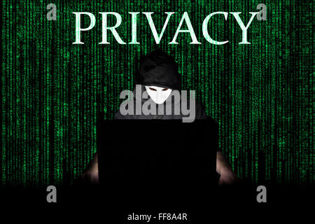 Ein maskierter Mann auf einen Laptop als Symbol für die Gefahren des Internets. Stockfoto