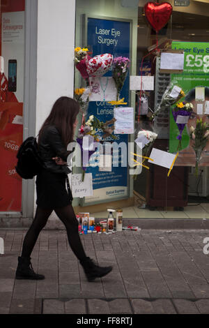 Donegall Place, Belfast, 11. Februar 2016. Eine junge Frau geht Vergangenheit Ort wo Mann obdachlos Belfast "Jimmy" starb am Sonntag früh Morning.Tributes von Blumen, Karten und Kerzen blieben am Tatort Credit: Bonzo/Alamy Live News Stockfoto