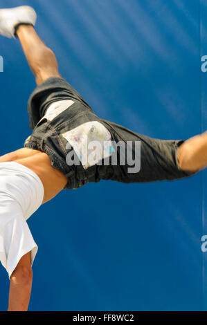 Rückansicht der ein junger Mann-Breakdance mit beiden Beinen in der Luft. Stockfoto