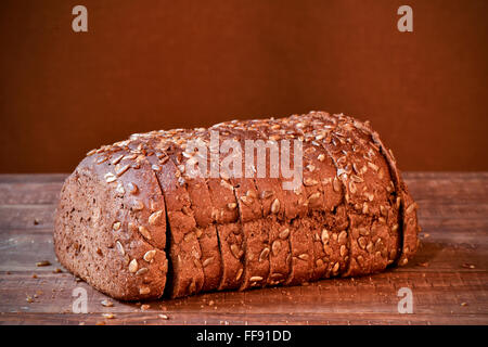 ein geschnittene Brot Roggen Brot mit Sonnenblumenkernen auf einer rustikalen Holzoberfläche Stockfoto