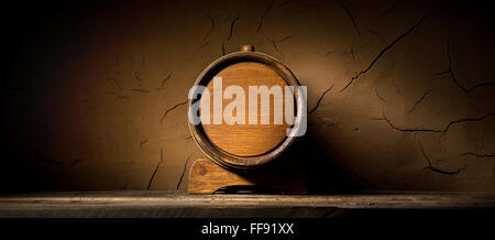 Holzfass in der Nähe von Lehm Wand im Keller Stockfoto