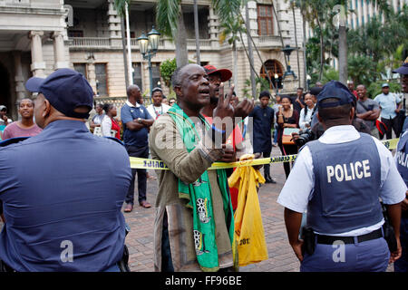 Durban, Südafrika. 11. Februar 2016. AN dem Tag inszeniert, dass South Affrica Präsident Jacob Zuma wurde die Rede zur Lage der Nation an das Parlament 2000 Kilometer entfernt in Kapstadt, eine kleine Gruppe von Demonstranten liefern einen Protest in Durban zu verlangen, den er zu beenden. Aber nicht alle waren sich einig, einschließlich dieses Zuma-Anhänger, die durch die Polizei Kordon lehnte. Bildnachweis: Giordano Stolley/Alamy Live-Nachrichten Stockfoto