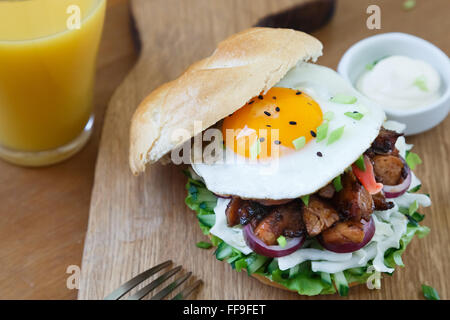 Einen köstlichen asiatischen Stil Hamburger mit Salat und Zwiebeln garniert und garniert mit einem Spiegelei. Stockfoto