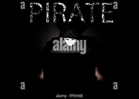 Ein maskierter Mann auf einen Laptop als Symbol für die Gefahren des Internets. Stockfoto