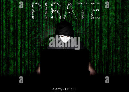 Ein maskierter Mann auf einen Laptop als Symbol für die Gefahren des Internets. Stockfoto