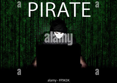 Ein maskierter Mann auf einen Laptop als Symbol für die Gefahren des Internets. Stockfoto