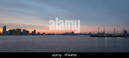 Einen wunderschönen Sonnenuntergang über den Hudson River, mit einem Segelboot in den Vordergrund, Blick auf Newport und Hoboken, NJ. Stockfoto