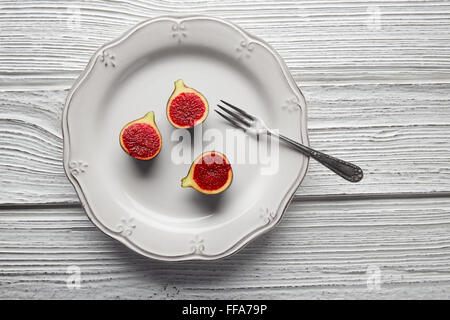 Feigen roh geschnittene Feigen Früchte auf weißen Teller und Tisch aus Holz Stockfoto