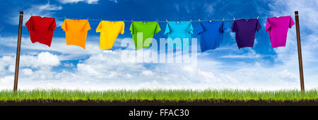 bunte t-Shirts auf der Wäscheleine auf grüner Wiese Stockfoto