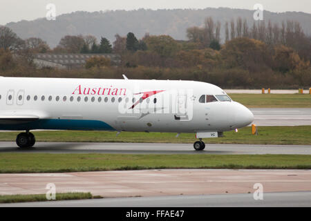 Austrian Airlines Fokker 100 mittelständische Twin-Turbinen-Kreiselbegläse Passagierflugzeug auf Manchester International Airport Asphalt Rollen. Stockfoto