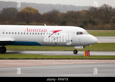 Austrian Airlines Fokker 100 mittelständische Twin-Turbinen-Kreiselbegläse Passagierflugzeug auf Manchester International Airport Asphalt Rollen. Stockfoto