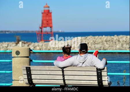 Ein Paar auf einer Bank sitzen und die Aussicht genießen, die Racine North Breakwater Leuchtturm und Lake Michigan in Racine, Wisconsin, USA. Stockfoto