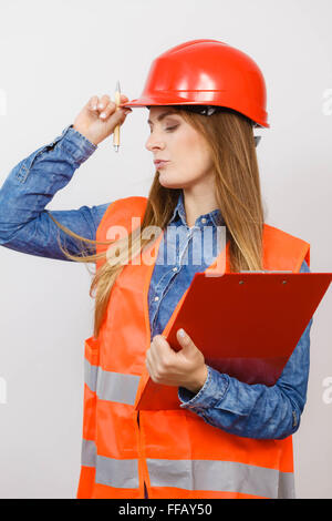 Frau Bau Arbeiter Builder strukturelle engineerin in rot orange Weste schwer Helm hält Stift Datei Pad. Sicherheit in der industriellen Stockfoto