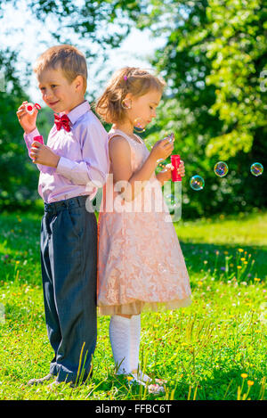 Vertikale Aufnahme der Kinder von 6 Jahren mit Seifenblasen auf Natur Stockfoto