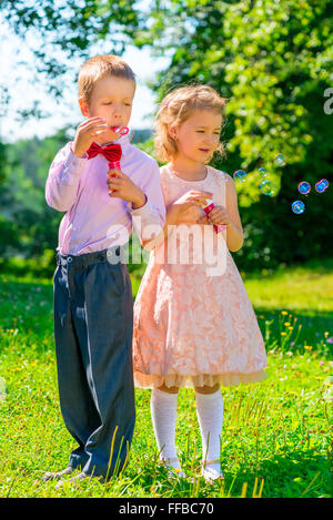 Mädchen und Jungen mit Seifenblasen im park Stockfoto