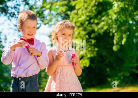 ein Junge und seine Freundin mit Seifenblasen im park Stockfoto