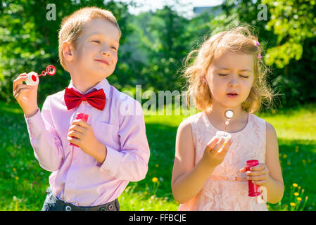 zwei Kinder in einem Park mit Seifenblasen in den Händen Stockfoto