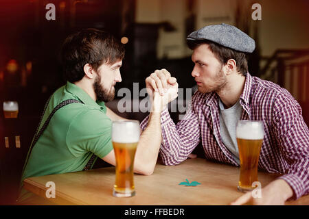 Zwei junge Männer sitzen in der Kneipe Armdrücken Stockfoto