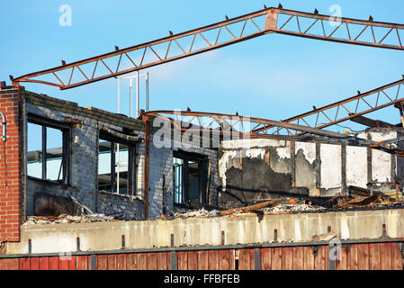 Ein kleines industrielle Gebäude niedergebrannt hat. Das Dach ist verschwunden und hat einige der Metalldach Strahlen durch die Hitze verbogen. Stockfoto