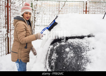 Frau, die Beseitigung von Schnee aus ihrem Auto in kalten Tag Stockfoto