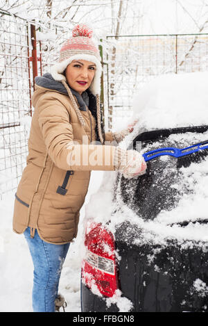 Frau in kalten Tag Schnee aus Auto entfernen Stockfoto