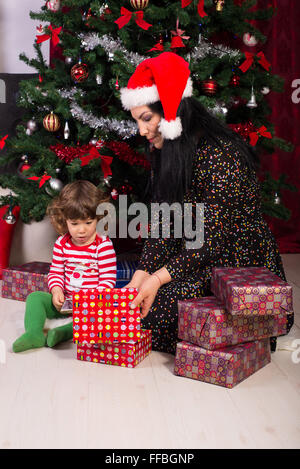 Sohn Mutter und Kleinkind Weihnachtsgeschenke in ihrer Heimat zu öffnen Stockfoto