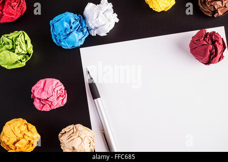 Zerknittert Farbe Papiere auf schwarzen Tisch mit weißem Papier und Kugelschreiber Stockfoto