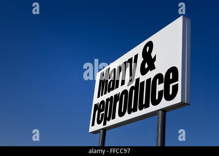 Große Anzeige-Panel, geprägt mit der Meldung "Marry und reproduzieren", isoliert auf blauen Himmel. Stockfoto