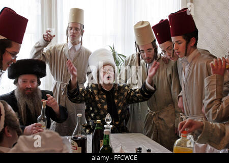 Während des jüdischen Festivals von Purim besucht eine Gruppe von orthodoxen jüdischen Jungen aus der Viznitz-Jeschiwa (Schule) verkleidet lokale Geschäftsleute, Geld für ihre Schule zu sammeln. Die Purim Rabbiner (Mitte) führt die Gruppe mit einem Lied, sie trinken Alkohol in jedem Haus, die sie im Laufe des Tages zu besuchen. Stockfoto