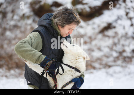 Mann umarmt mit Husky im Winterwald Stockfoto