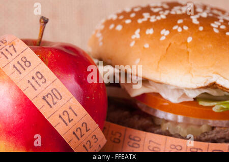 Hamburger und Apfel mit Messgerät Closeup. Diät-Konzept Stockfoto