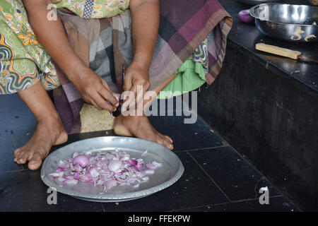 Mumbai, Indien - 28. Oktober 2015 - Frau schneiden Chili und Zwiebeln auf einem traditionellen schneiden Hocker in indischen Küche Stockfoto