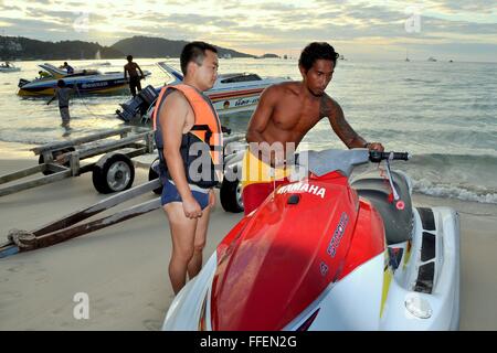 Phuket, Thailand: Thai Mann (rechts) beschreibt, wie ein Jet-Skiboot, ein chinesischer Tourist in Patong Beach zu bedienen Stockfoto