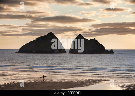 Eine Surfer geht über den Strand in Holywell Bay, North Cornwall im Abendlicht Stockfoto