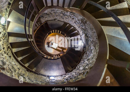 Auf der Suche nach unten eine Wendeltreppe auf eine Frau in einem spanischen Turm an. Stockfoto