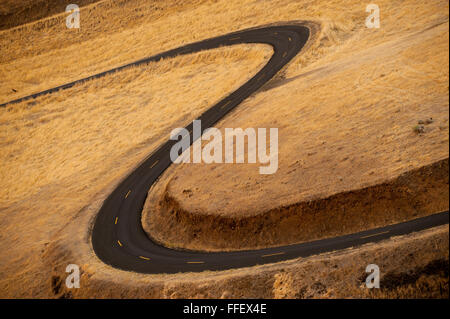 Eine geschwungene zweispurige Asphalt Straße windet sich durch die Hügel des östlichen US-Bundesstaat Washington. Stockfoto