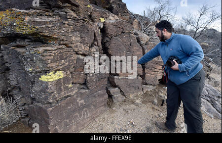 Suchscheinwerfer, Nevada, USA. 12. Februar 2016. Regisseur David Lamfrom der kalifornische Wüste und National Wildlife weist darauf hin Petroglyphen auf einem Felsvorsprung Felsen wie er hohe Wüstengebiet der Burg Berge Montag, 1. Februar 2016 Touren. Eine 21.000 Hektar großen Parzelle südwestlich von Searchlight, Nevada in Kalifornien wird vorgeschlagen, als nationales Denkmal zum Schutz einer Fläche weggelassen, wenn die 1,5 Millionen Hektar großen Mojave National Preserve 1994 gegründet wurde. US-Präsident Barack Obama nutzt seine Autorität unter dem Antiquities Act erstelle ich drei Denkmäler der Mojave-Wüste auf fast 2 Millionen Hektar einschließlich der Stockfoto