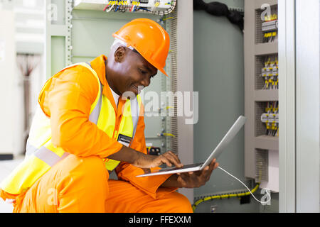 junge afrikanische amerikanische Ingenieur mit Laptop im Maschinenraum Kontrolle Stockfoto