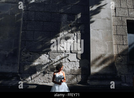 Braut posiert auf Steinmauer Hintergrund Stockfoto