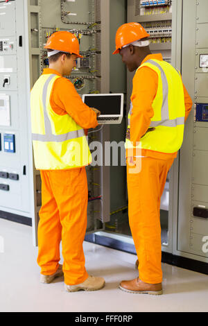 Heckansicht des erfolgreichen Techniker mit Laptop im Kontrollraum Stockfoto