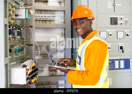 Afrikanische elektrischen Arbeiter mit Laptop-Computer Check-Transformator Stockfoto